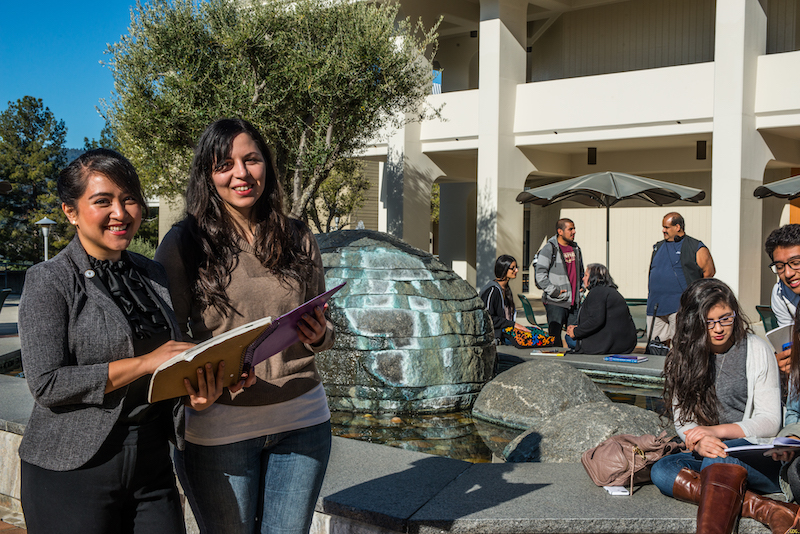 Staff member stand in the upper quad while smiling and looking at the camera