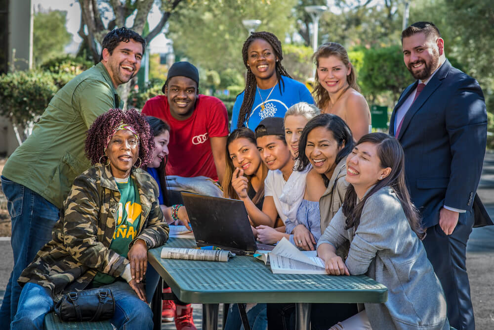 Peer mentors and students gathered at the Outdoor Amphitheatre on campus smile for a professional photo.