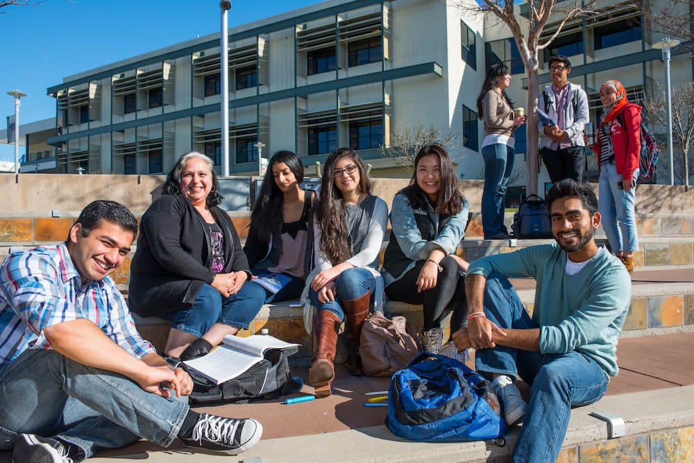 Peer mentors and students gathered at the Outdoor Amphitheatre on campus smile for a professional photo.